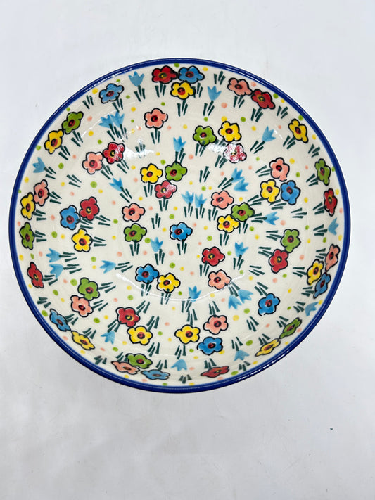 Top-down overhead view looking into a Ceramika Artystyczna Polish pottery shallow bowl, showing a continuous dark blue rim and a fully decorated interior basin featuring hand-painted multi-colored spring flowers.
