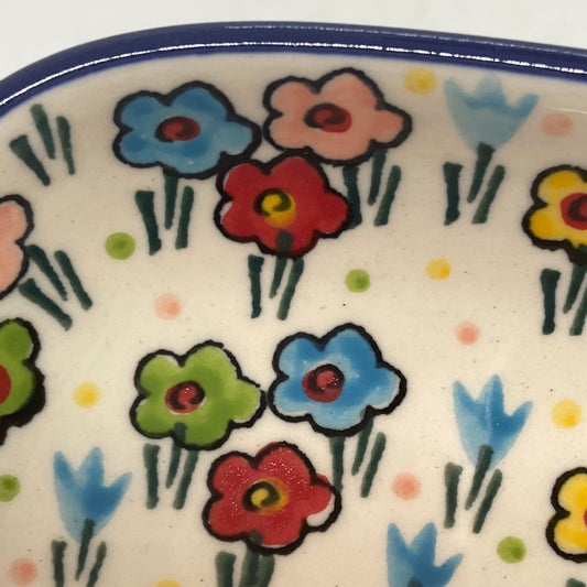 Extreme close-up of a Ceramika Artystyczna Polish pottery rectangular tray corner, showing a thin dark blue rim and distinct artisan brushstrokes on hand-painted multi-colored spring flowers