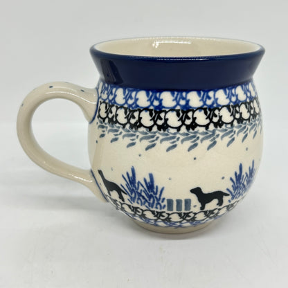 Straight-on side profile of a Ceramika Artystyczna Polish pottery bubble mug with the handle on the left, featuring black dog silhouettes, blue plants, layered borders, and a solid dark blue rim.