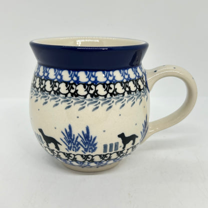 Straight-on side profile of a Ceramika Artystyczna Polish pottery bubble mug with the handle on the right, showing black dog silhouettes, blue plants, layered borders, and a solid dark blue rim.