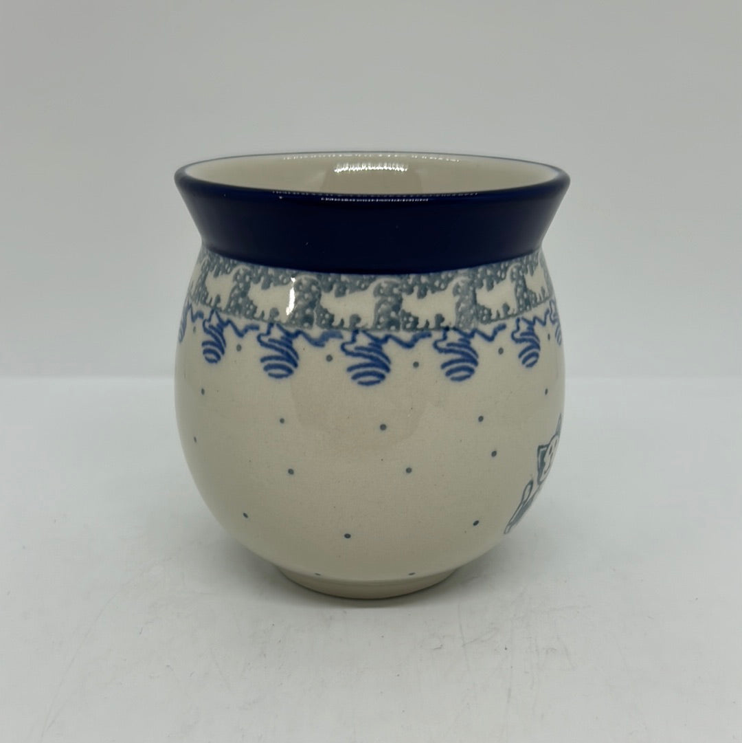 Straight-on view of the back of a Ceramika Artystyczna Polish pottery bubble mug, showing a cream background with blue dots, a continuous cat silhouette border, and a dark blue rim with no handle visible.