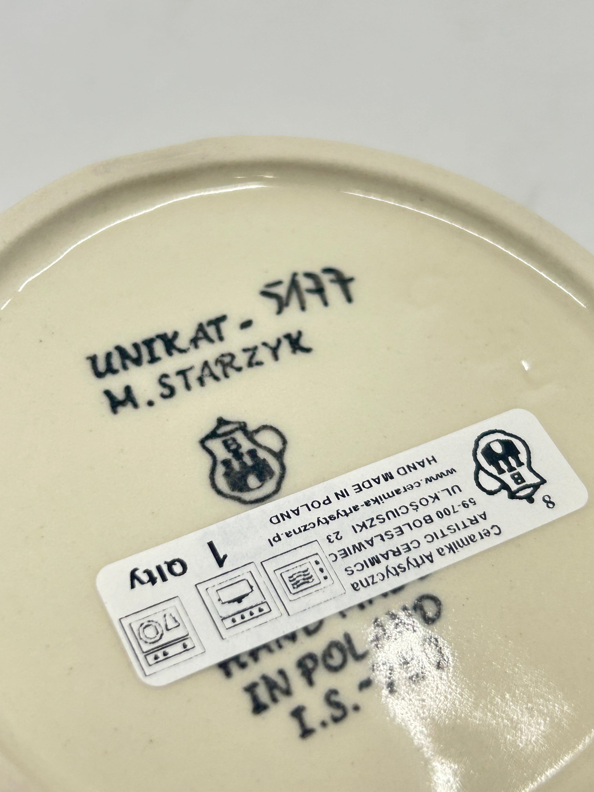 Bottom of a round Ceramika Artystyczna Polish pottery trinket box showing the Unikat 5177 stamp, M. Starzyk artist name, Ceramika Artystyczna's logo, and 1st Quality sticker.