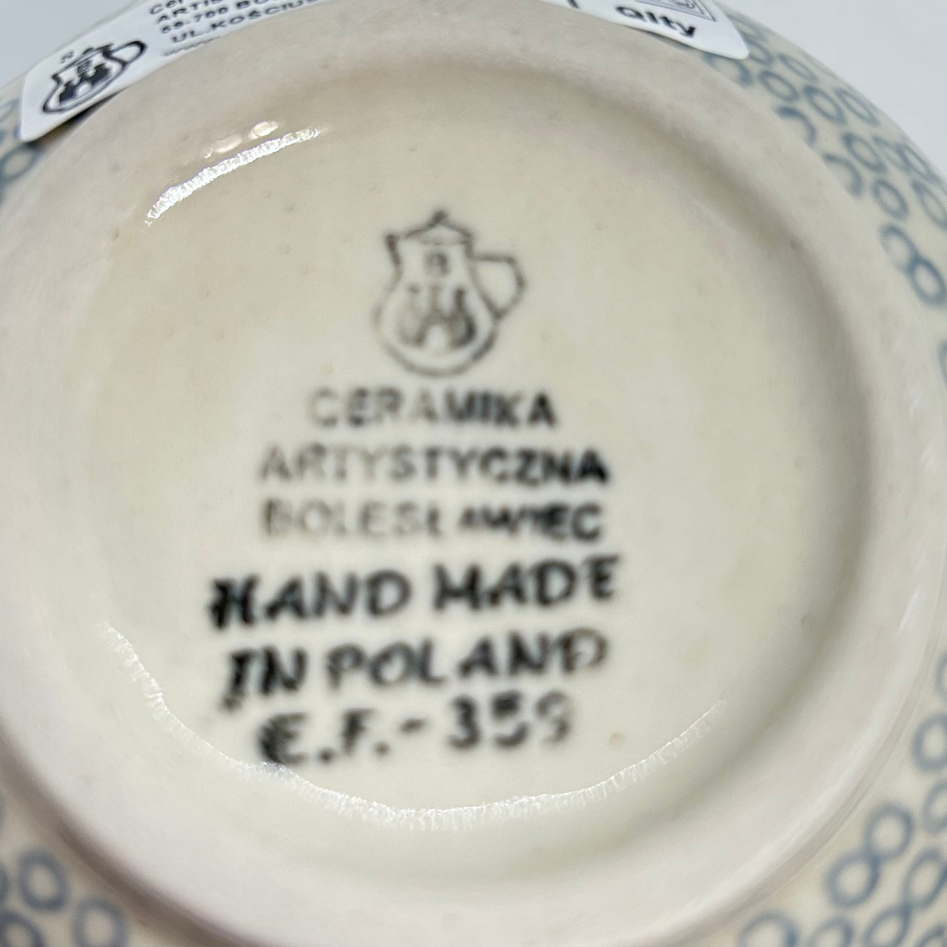 Bottom base of a Ceramika Artystyczna Polish pottery bubble mug, showing the official factory stamp, a partial retail sticker, and an unglazed foot ring.