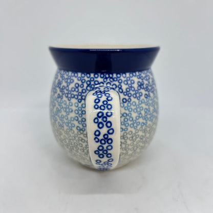Straight-on view focusing on the dotted handle of a Ceramika Artystyczna Polish pottery bubble mug, flanked by a gradient pattern of blue and grey stamped circles, and a solid dark blue rim.