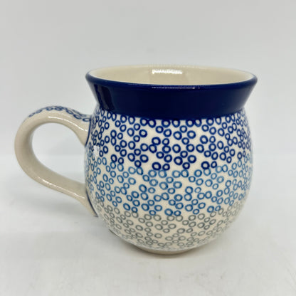 Straight-on side profile of a Ceramika Artystyczna Polish pottery bubble mug with the handle on the left, featuring a gradient pattern of blue and grey circular rings and a solid dark blue rim.