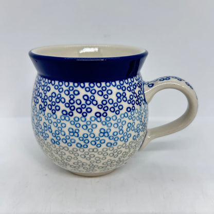 Straight-on side profile of a Ceramika Artystyczna Polish pottery bubble mug with the handle on the right, featuring a gradient pattern of blue and grey circular rings and a solid dark blue rim.