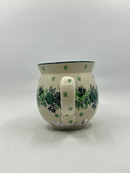 Straight-on view of the handle of a Ceramika Artystyczna Polish pottery bubble mug, showing green flower stamps on the handle and the botanical rose and fern pattern wrapping around both sides.