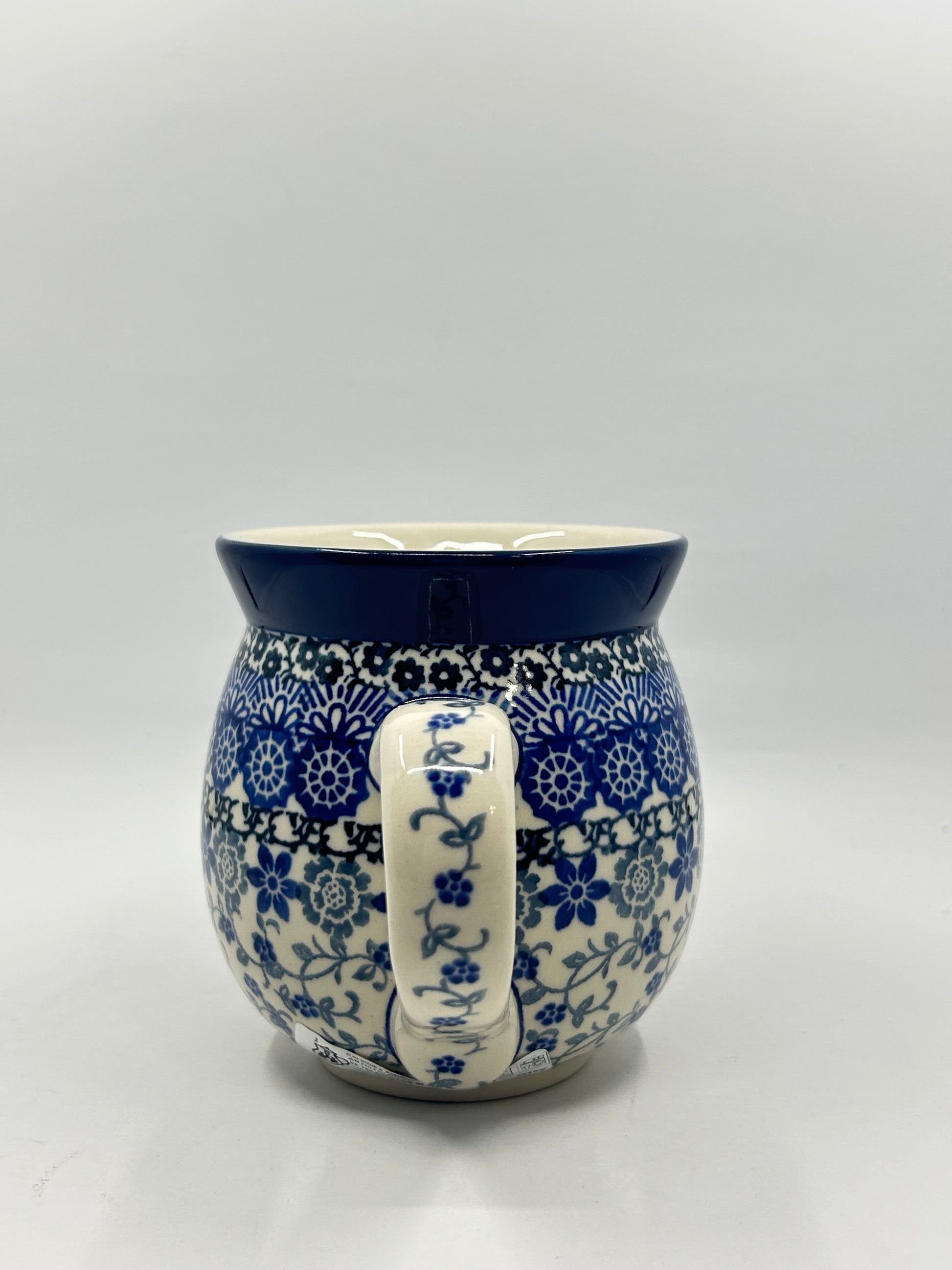 Straight-on view focusing on the patterned handle of a Ceramika Artystyczna Polish pottery bubble mug, flanked by multi-banded blue geometric and floral patterns and a solid dark blue rim.