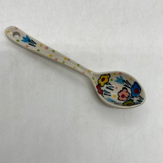 Overhead view of a Ceramika Artystyczna Polish pottery decorative ceramic spoon showing a hand-painted spring floral pattern and a hanging hole at the handle tip.