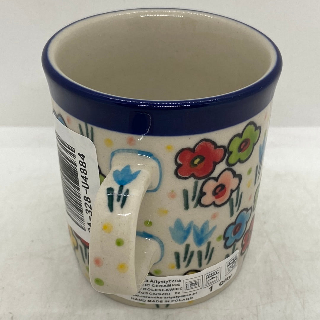 Angled view of a Ceramika Artystyczna Polish pottery coffee mug showing a hand-painted tulip motif on the handle, a barcode sticker, and a dark blue rim.