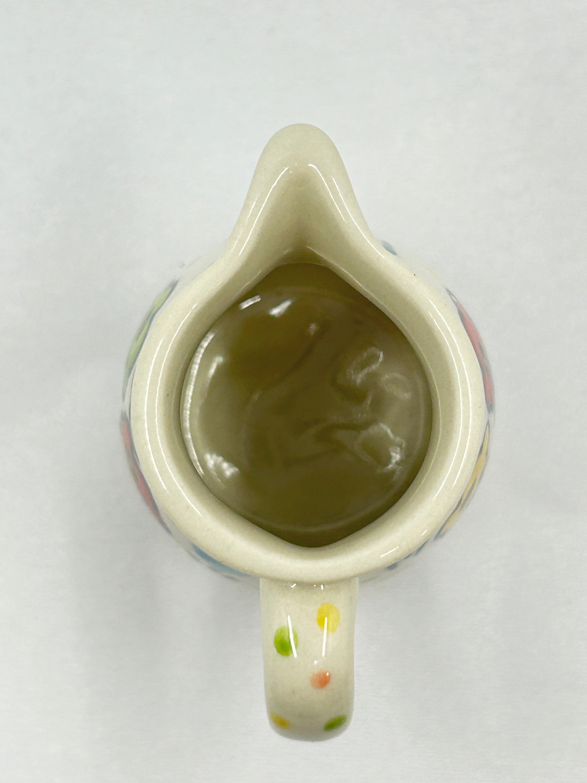 High-angle overhead view of a Ceramika Artystyczna Polish pottery creamer pitcher looking into the interior basin, showing the pouring spout and dotted handle.