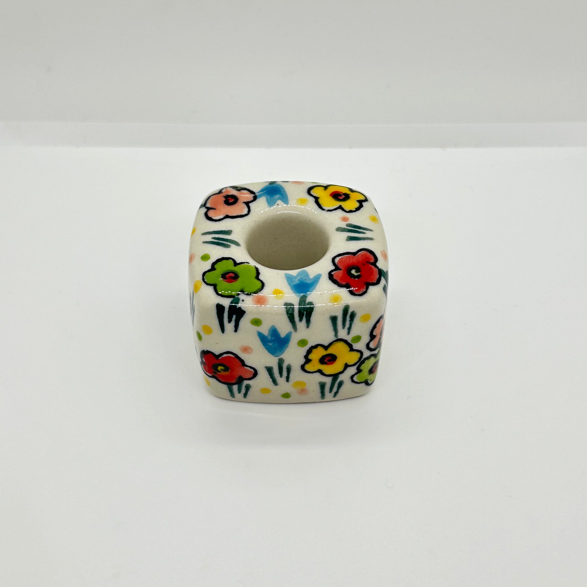 High-angle overhead view of a Ceramika Artystyczna Polish pottery cube candle holder showing the central socket and hand-painted spring flowers across the top and sides.