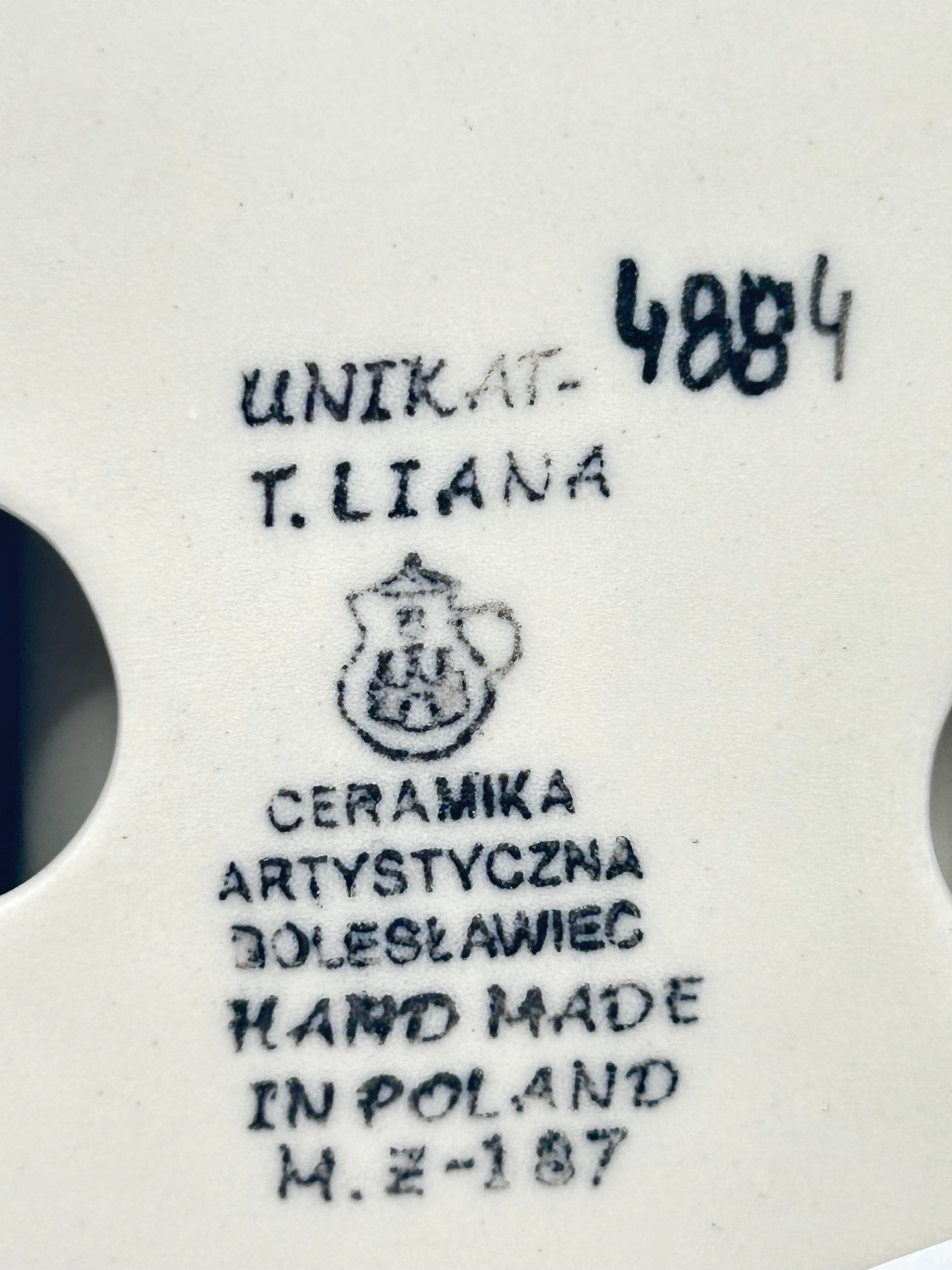 Close-up of the unglazed base of a Ceramika Artystyczna napkin holder showing the T. Liana UNIKAT 4884 signature and the Bolesławiec factory stamp.