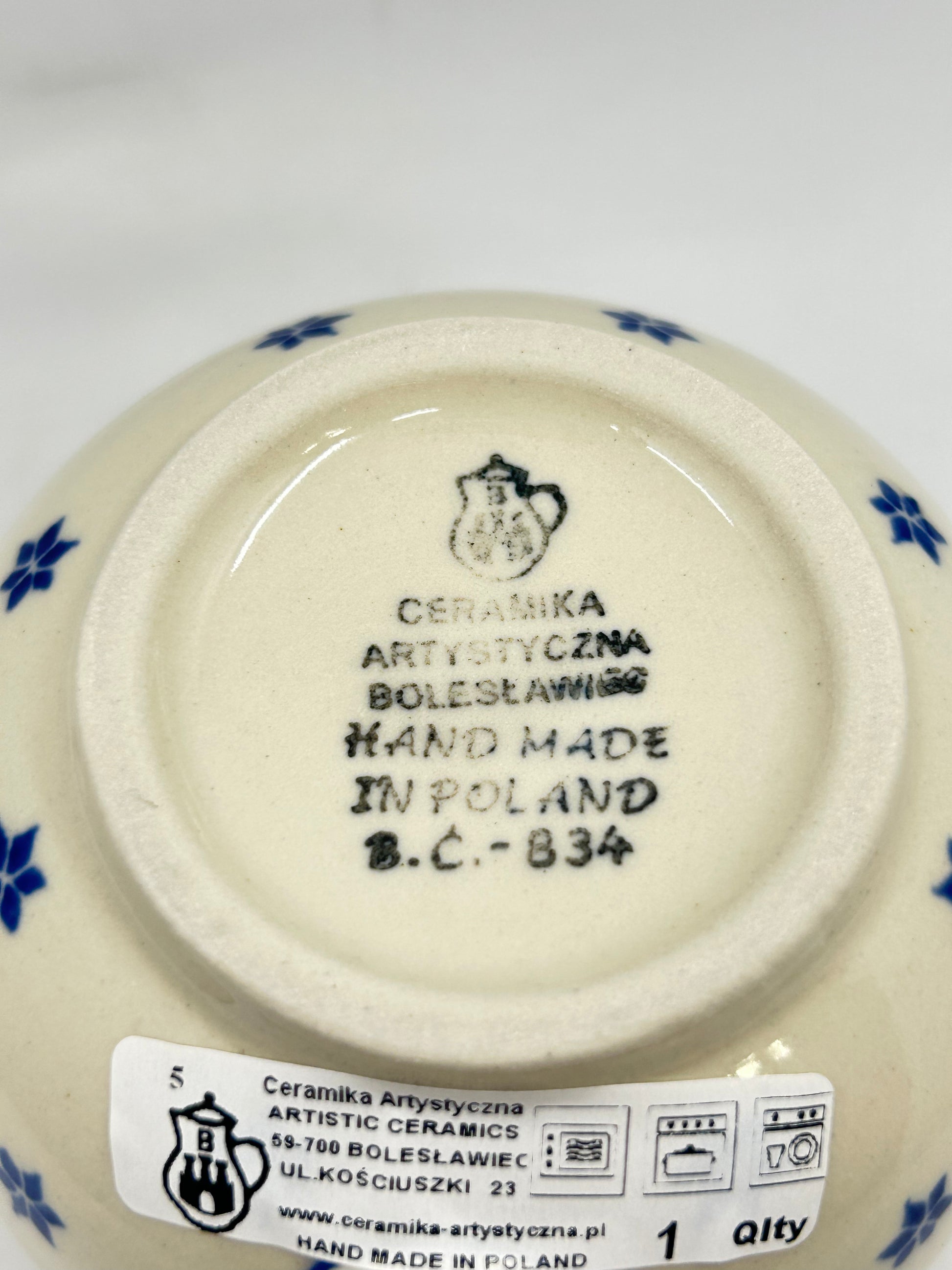 Bottom base of a Ceramika Artystyczna Polish pottery bubble mug, showing the official factory stamp, a first-quality retail sticker, and an unglazed foot ring.