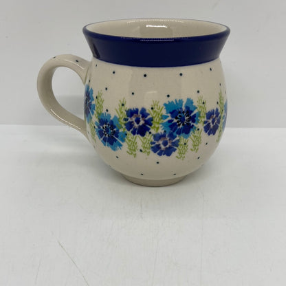 Straight-on side profile of a Ceramika Artystyczna Polish pottery bubble mug with the handle on the left, featuring hand-painted blue cornflowers, green stems, a dotted cream background, and a solid dark blue rim.