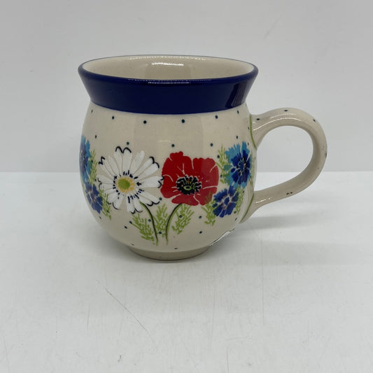 Straight-on side profile of a Ceramika Artystyczna Polish pottery bubble mug with the handle on the right, featuring a hand-painted red poppy, white daisy, blue flowers, and a solid dark blue rim.