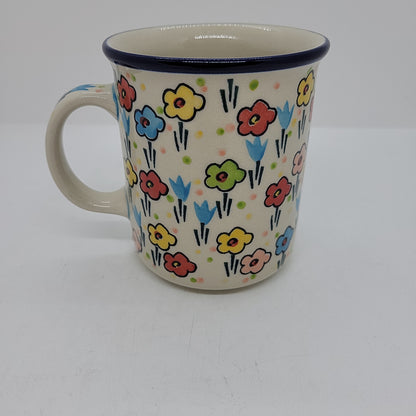 Front-facing view of a Ceramika Artystyczna Polish pottery coffee mug showing the side handle, dark blue rim, and hand-painted spring floral pattern