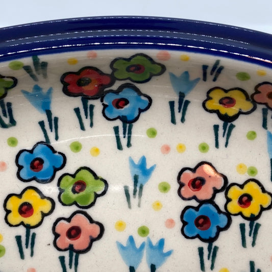 Extreme close-up of the interior of a Ceramika Artystyczna Polish pottery divided serving dish, showing a thick dark blue rim and distinct artisan brushstrokes on hand-painted multi-colored spring flowers