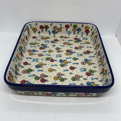 Elevated view of a Ceramika Artystyczna Polish pottery large rectangular baking dish showing the interior floral pattern and dark blue rim.