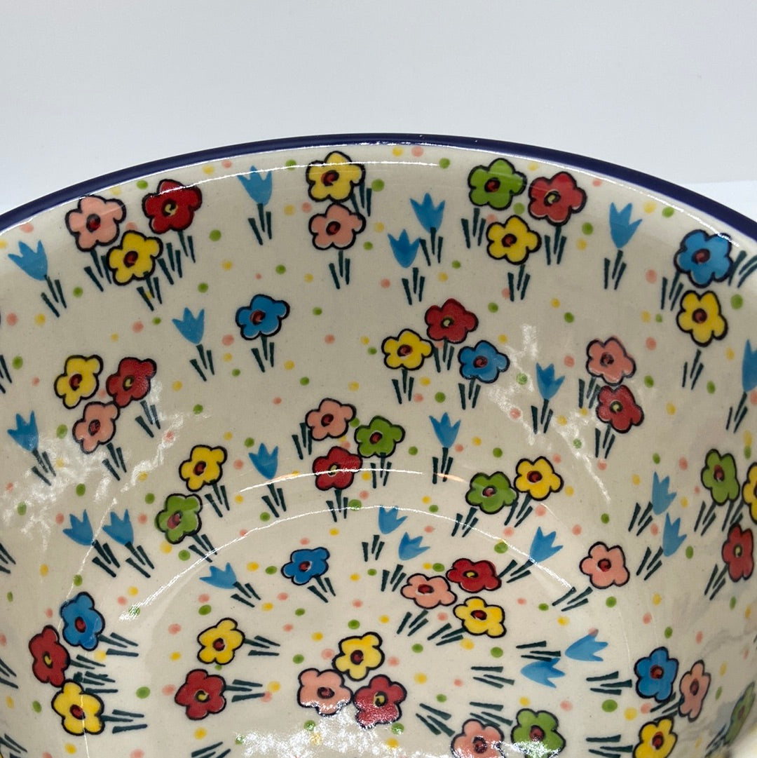 Extreme close-up of the interior wall of a Ceramika Artystyczna Polish pottery deep round bowl, showing high-gloss reflections over hand-painted multi-colored spring flowers.