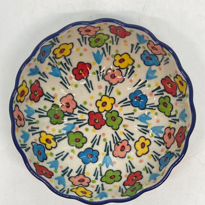 Top-down overhead view looking into a Ceramika Artystyczna Polish pottery scalloped bowl, showing a wavy dark blue rim and a fully decorated interior featuring hand-painted multi-colored spring flowers.